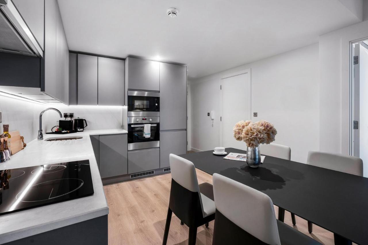 Citysuites 2 Aparthotel Manchester Exterior photo The photo shows a modern kitchen and dining area. The kitchen features sleek gray cabinets, a countertop with an embedded cooktop, and built-in appliances, including an oven and microwave. There’s a small coffee maker on the counter. Adjacent to the 