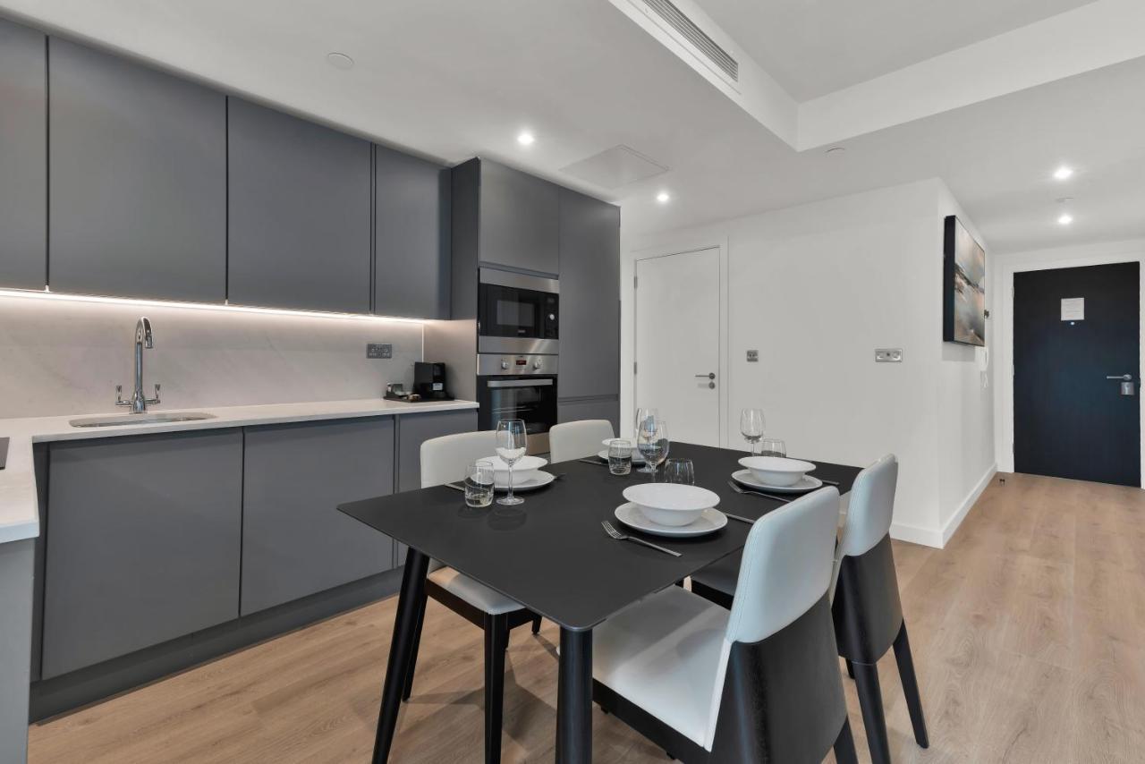 Citysuites 2 Aparthotel Manchester Exterior photo The photo shows a modern kitchen and dining area. There are sleek gray cabinetry and countertops, with a built-in oven and microwave. The kitchen is well-lit, featuring under-cabinet lighting that adds to the contemporary feel. In the dining area, th