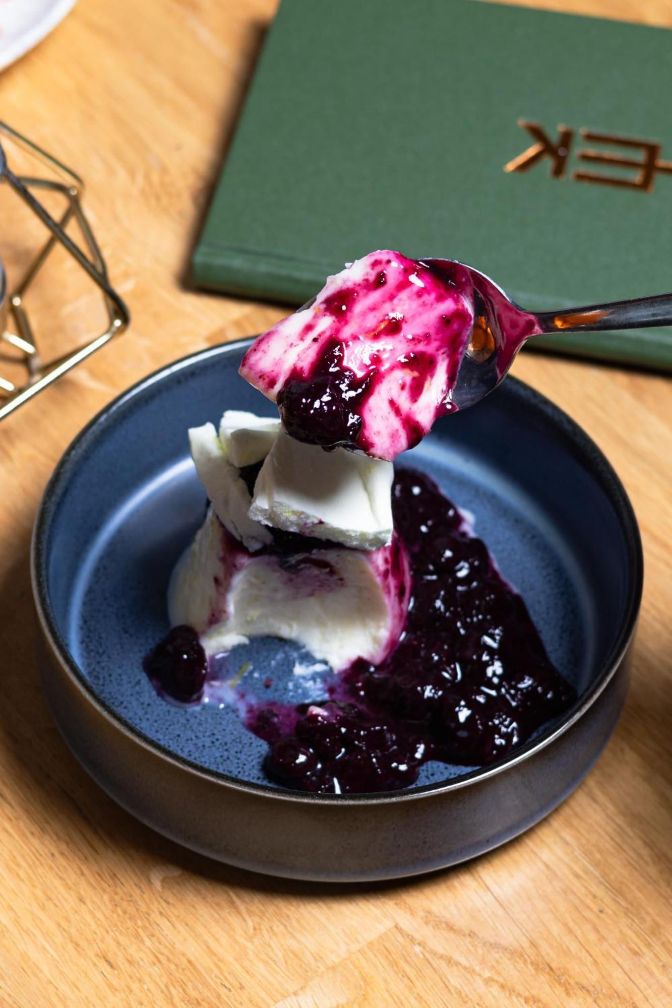 Citysuites 2 Aparthotel Manchester Exterior photo The photo shows a serving of dessert, likely a type of panna cotta or a creamy custard, partially dished out and accompanied by a rich berry sauce, possibly made from blueberries or blackberries. A spoon with some of the dessert and sauce is hovering